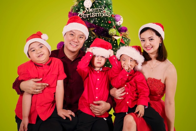 Parents sit with their sons near a christmas tree