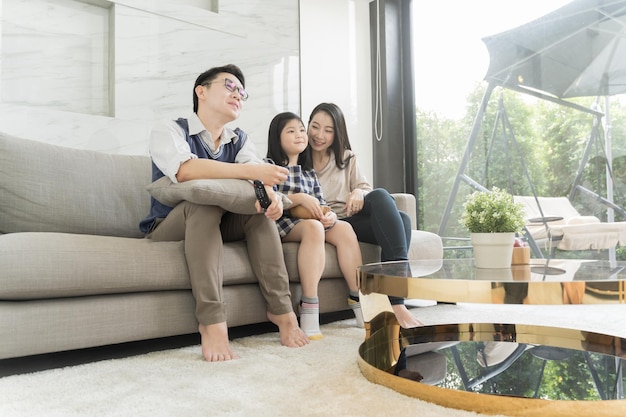 Parents sitting with daughter on sofa in living room at home