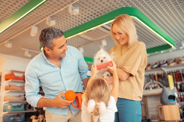 Parents smiling while daughter playing with dog