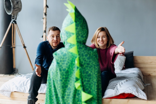 Parents and son in dragon cape look funny posing in the room