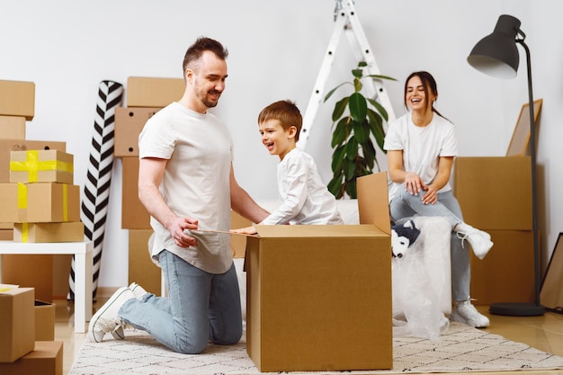 Родители и сын упаковывают коробки и переезжают в новый дом