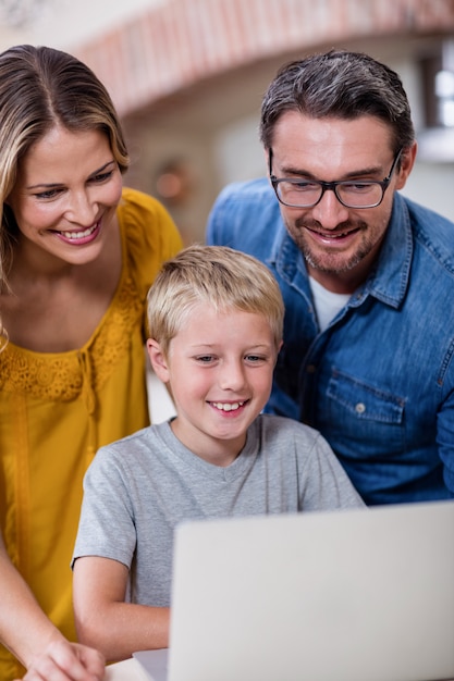 Parents and son using laptop in kitchen