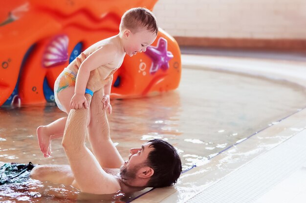 Родители учат ребенка плавать в детском бассейне