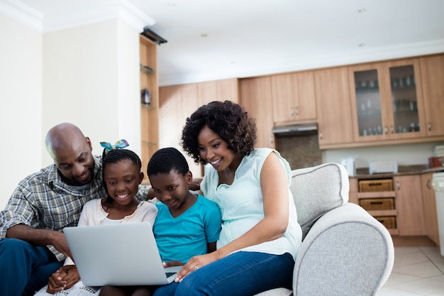 Parents and their children using laptop in living room