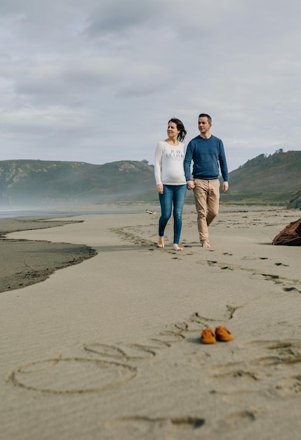 Parents walking with baby name Oliver written in the sand