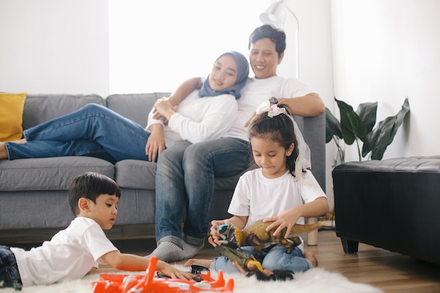 Photo parents watching kids playing toys at home