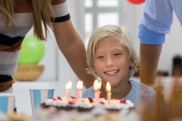 誕生日のケーキを見ている男の子と両親