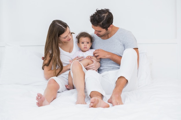 Parents with child sitting on bed 