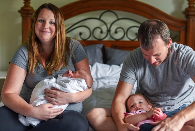 Photo parents with children sitting on bed at home