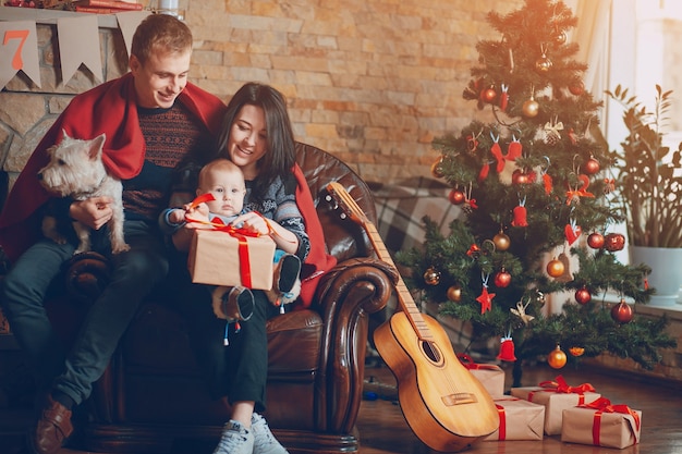 Parents with a dog and a baby and a guitar resting on the couch