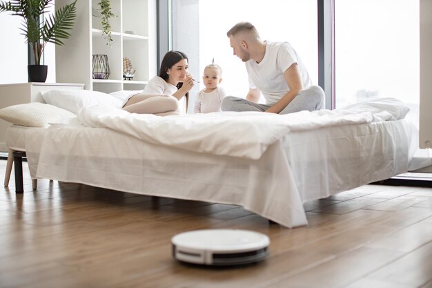 Parents with kid using smart gadget for cleaning at home