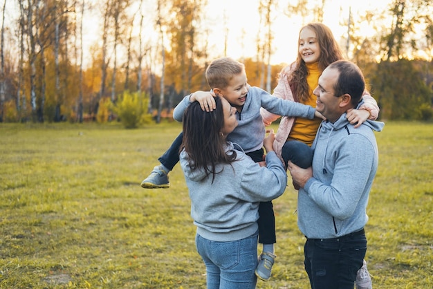 Родители с детьми отдыхают в парке, семья обнимается