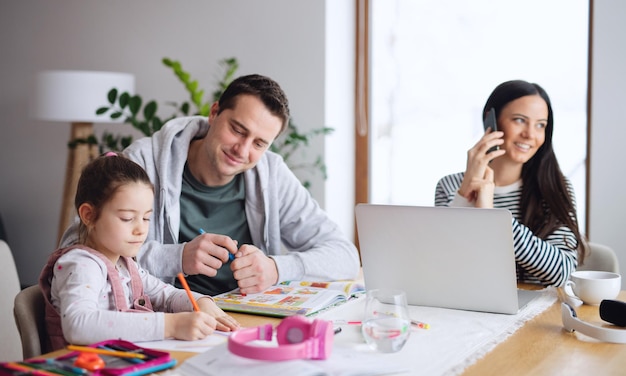 Parents with school girl indoors at home, distance learning and home office concept.