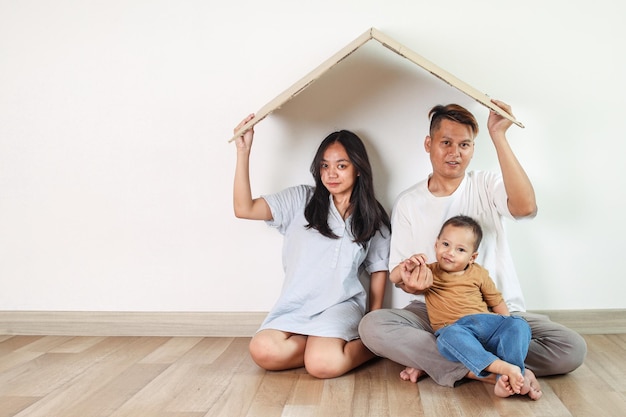 Photo parents with son holding roof over heads family insurance concept