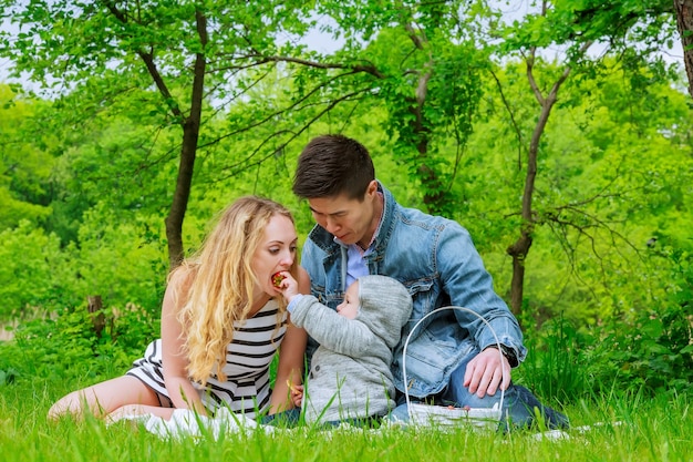 Parents with son play on the lawn in the park