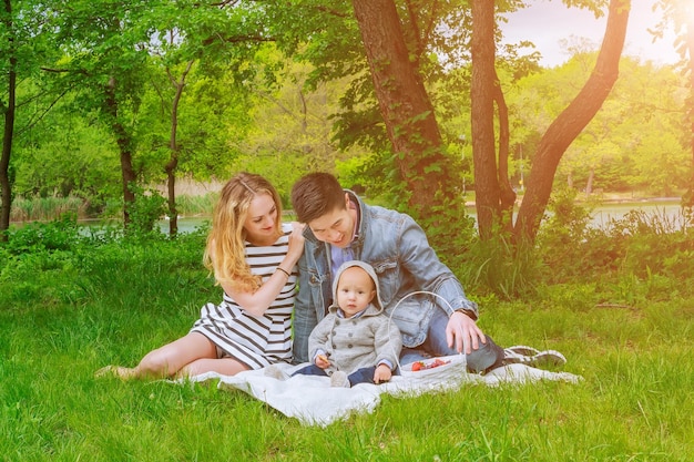 Parents with son play on the lawn in the park