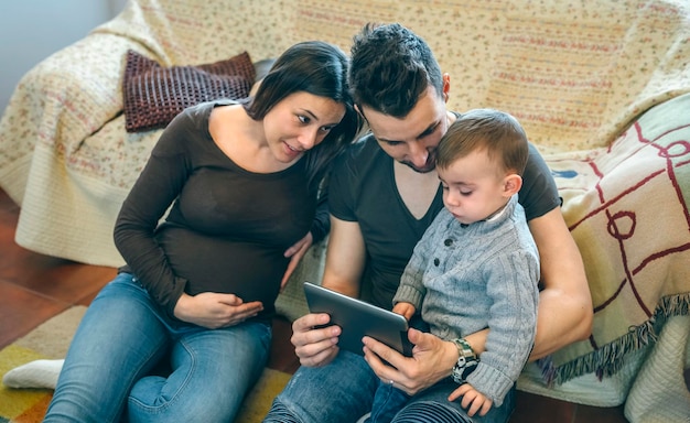 Photo parents with son using digital tablet while sitting in living room