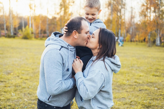 Parents with their son are walking in the park having fun smiling and kissing adoption kid happy peo