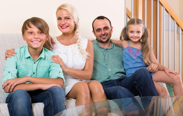 Photo parents with two children posing in home interior