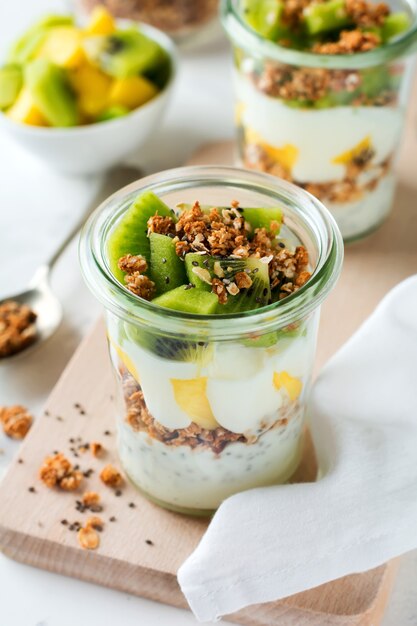 Parfait van yoghurtgranola met mango, kiwi, tropisch fruit en chiazaad, gelaagd dessert of ontbijt. Selectieve aandacht.