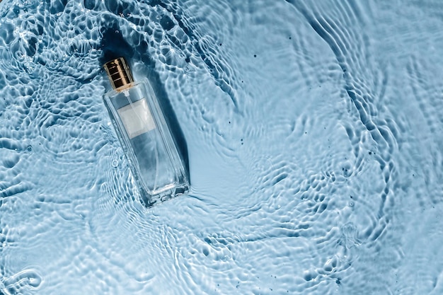 Parfumflesje op blauwe water golvende achtergrond Frisse zee geur concept Dames en heren essentie