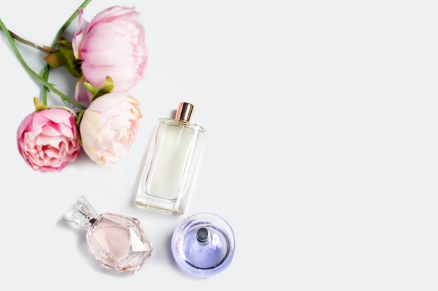 Parfumflesjes met bloemen op lichte ondergrond. Parfumerieën, cosmetica, geurcollectie