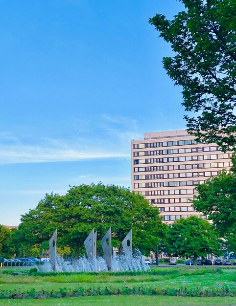 Park by buildings against blue sky