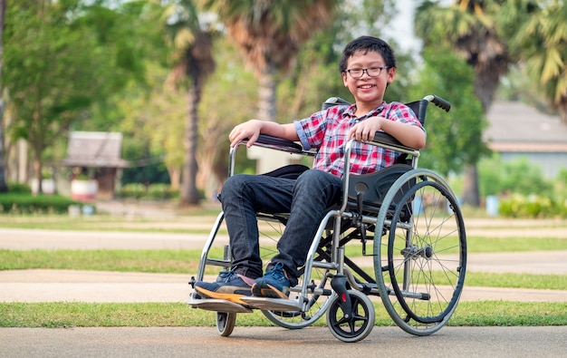 In the park, a child in a wheelchair. Take a closer look at his steering wheel. medical concept that is healthy and Happy disabled kid concept.