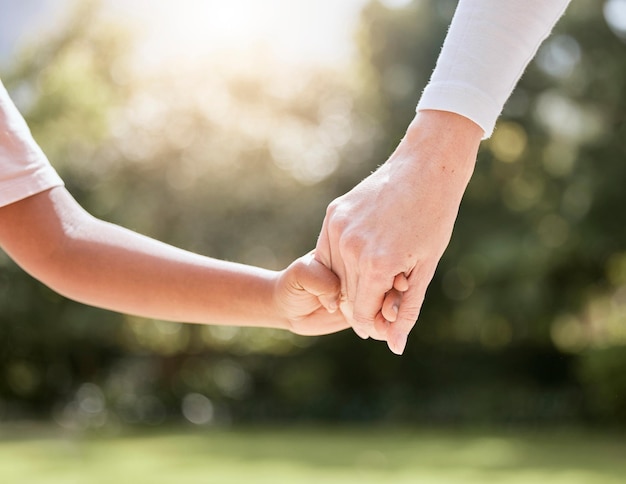 Park family and parent holding hands with child enjoying nature summer holiday and weekend together Bonding support and person holding hand of young kid with affection love and care in nature