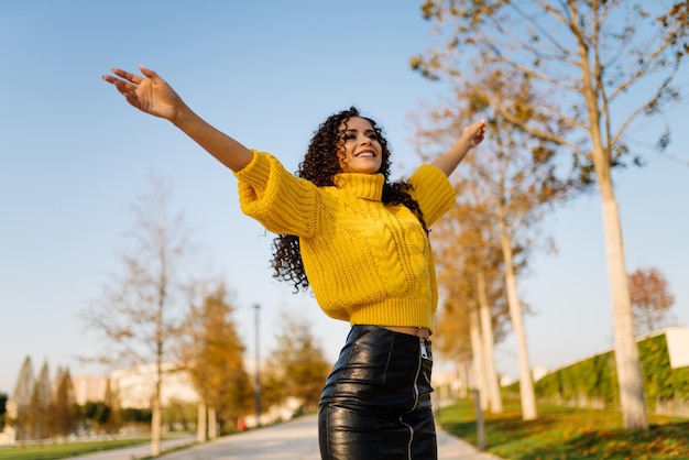 On the park track with a joyful look the girl victoriously raised her hands up and spread them to th