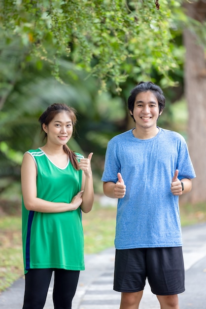 In the park, a young couple of runners pose for a portrait. Sport and love as a concept