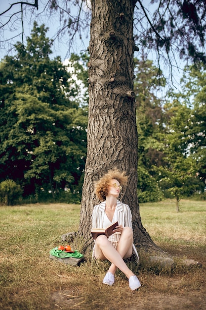 Foto nel parco. giovane donna seduta sotto l'albero nel parco