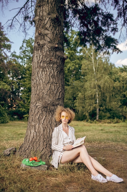 In the park. Young woman sitting under the tree in the park