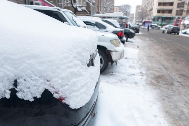 Припаркованные автомобили покрыты снегом