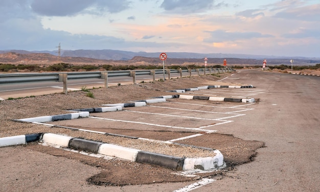 Parkeerplaatsen bij rustruimte nabij hoofdweg, woestijnlandschap achtergrond