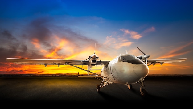 Parking airplane at the airport runway on the beautiful sunset background