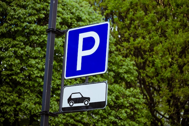 Segno di parcheggio per auto su uno sfondo verde naturale di alberi