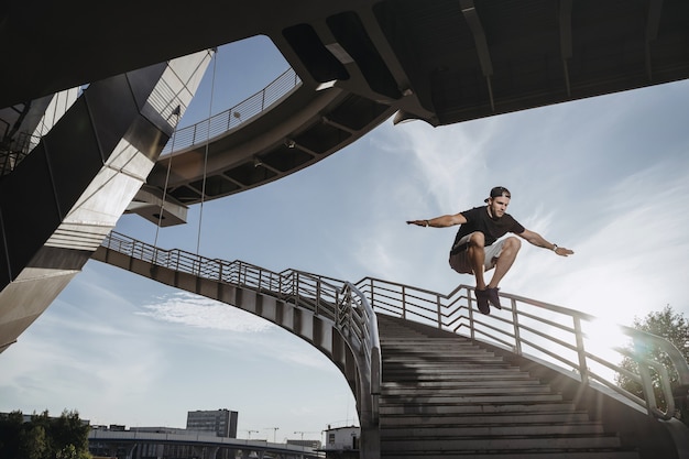 도시에서 Parkour 선수 훈련. 남자는 계단을 통해 큰 자유 달리기 점프를 수행합니다.