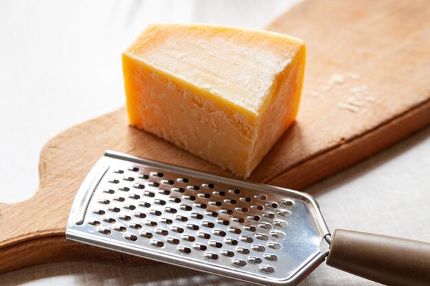 Сыр пармезан Кусок сыра и терка на деревянной доске Мелкая терка для натирания сыра