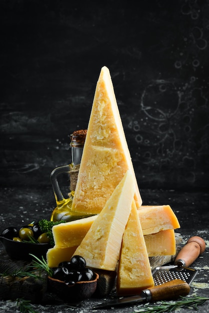黒い石の背景にパルメザンチーズのパルメザンチーズの断片上面図あなたのテキストのための空きスペース