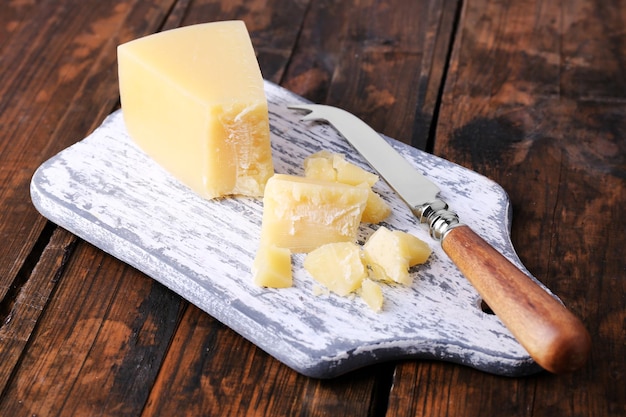 Parmezaanse kaas op snijplank met mes op houten tafel achtergrond