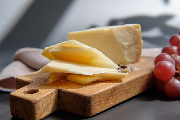 Parmigiano Cheese on wooden cut board with grape berries