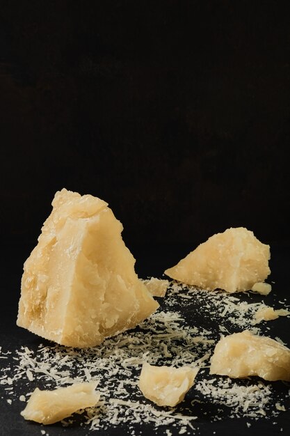 Кусочки пармезана на старом кухонном столе, спелый сыр с фермы. Натуральный продукт средиземноморской кухни