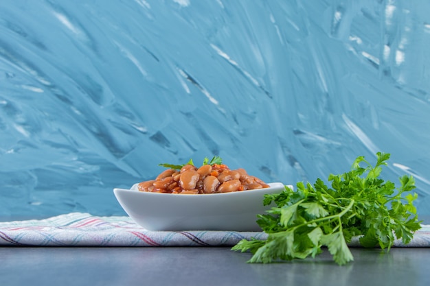 Parsley and beans bowl on a tea towel , on the blue background.