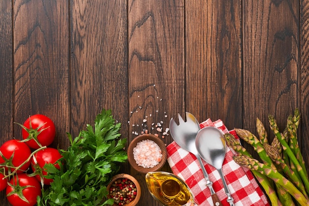 Parsley parsley tomato garlic olive oil pepper salt and salad fork and spoon on wooden cooking background Food cooking background Ingredients for cooking food background Mock up Top view