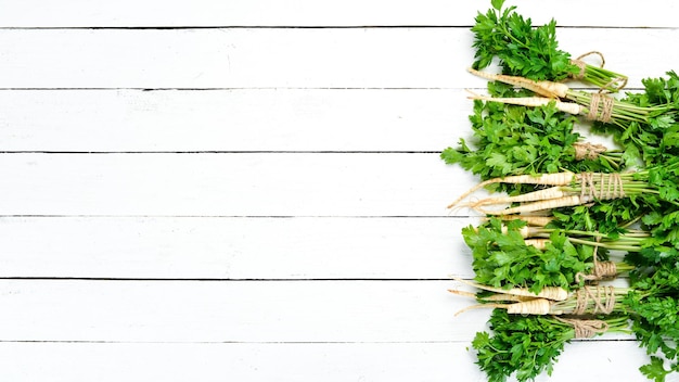 Parsley root on a white wooden background Top view Free space for your text