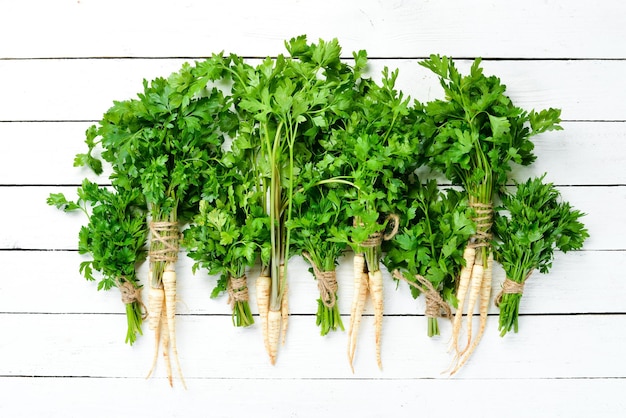 Parsley root on a white wooden background Top view Free space for your text