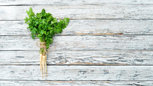 Parsley root on a white wooden background Top view Free space for your text