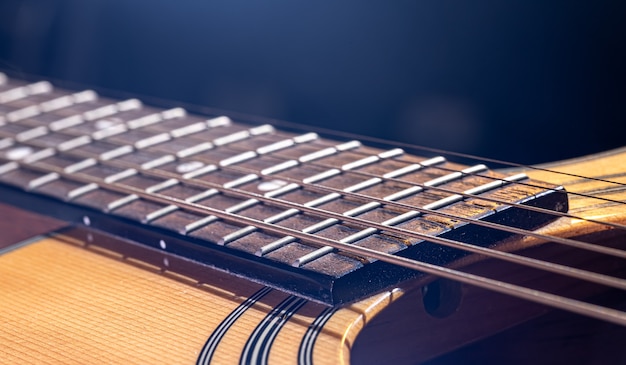어쿠스틱 기타의 일부, 하이라이트가 있는 검정색 배경에 현이 있는 기타 지판.