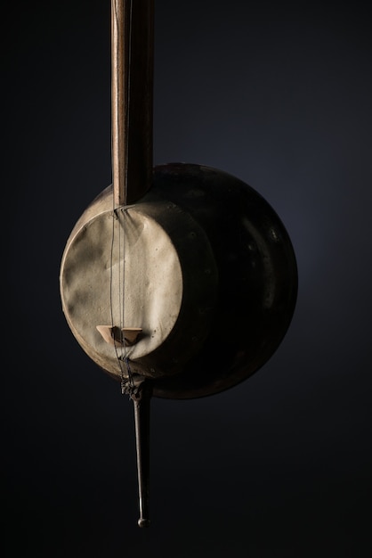 Part ancient Asian stringed musical instrument on black background with backlight